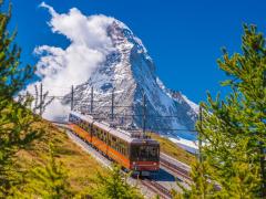 ></center></p><h2>Top of Switzerland (GoldenPass)</h2><p>INDIVIDUEL (8 jours, sans nuit à bord) Les 3 plus belles montagnes suisses à découvrir avec les trains de la GoldenPass line. Mont Rigi, Jungfrau, Glacier 3000 : vous contemplez le toit de l'Europe !</p><p>A partir de: 1965 €</p><h2>Voyages en train en Suisse : l'histoire</h2><p>Au milieu du XIXe siècle, la Suisse s’ouvre tardivement à la   folie ferroviaire  qui a gagné l’Europe depuis plusieurs années. Mais une fois le mouvement est lancé, les lignes se développent et des gares se construisent très vite. En 1860, la le pays possède le réseau ferré le plus dense du monde. Aujourd’hui encore, les Helvêtess détiennent le record du monde de kilomètres annuels de voyage en train  : plus de 2000 km par habitant !</p><p>Le  voyage en train en Suisse s'est développé grâce au commerce et à l’apparition de technologies innovantes comme la crémaillère. Le  train suisse de montagne a mis le pays  à la portée des touristes aisés, permis le développement du tourisme et l'apparition des premiers voyages organisés en train en Suisse.</p><h2>Le grand tour de Suisse en train</h2><p>Vous connaissez peut-être le 
